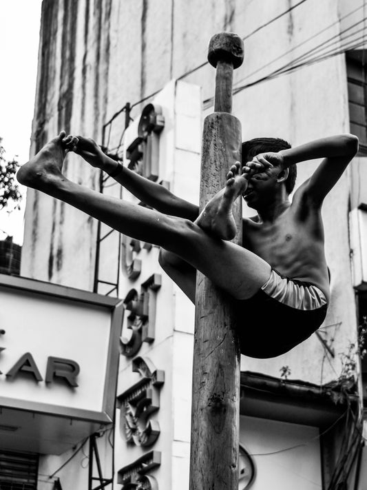 young hindu boy hanging on a pole in yoga position. bikinn.com/blog