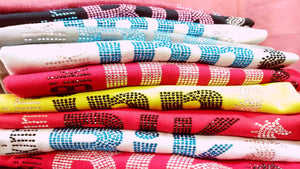 photo of a pile of folded t-shirts in multicolored colorways with glittering crystal prints