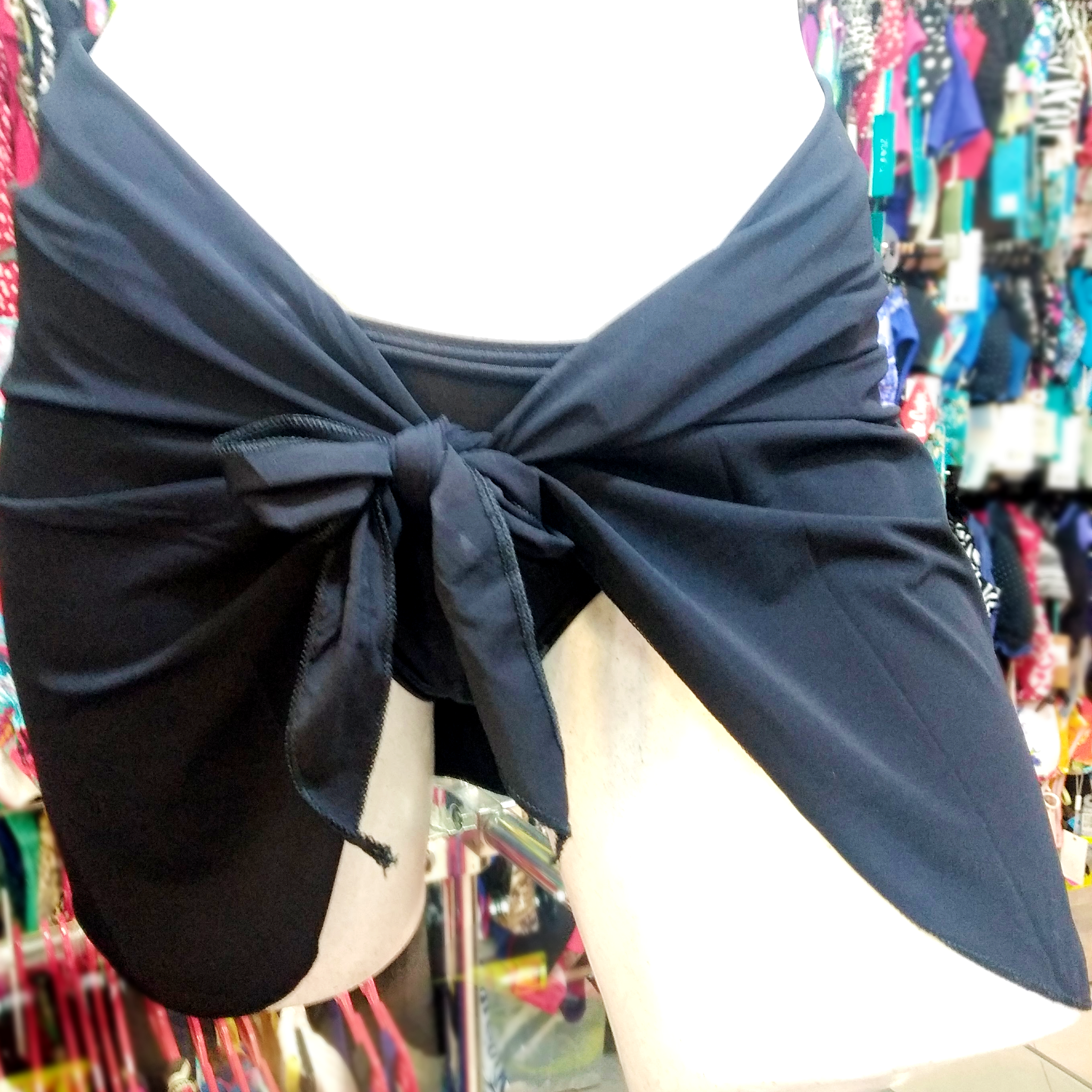 front of a black mini stretchy pareo tied around a white mannequin wearing a black bikini bottom.