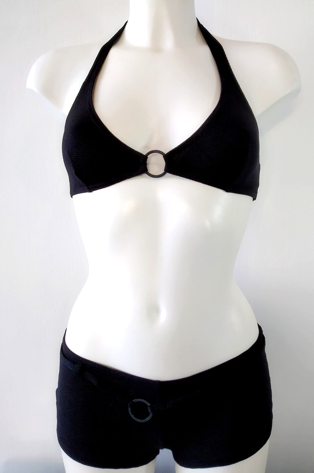 Two-piece black swimsuit, halter bra embellished with a black metal ring and low shorty bottom, black bikini. bikinn.com