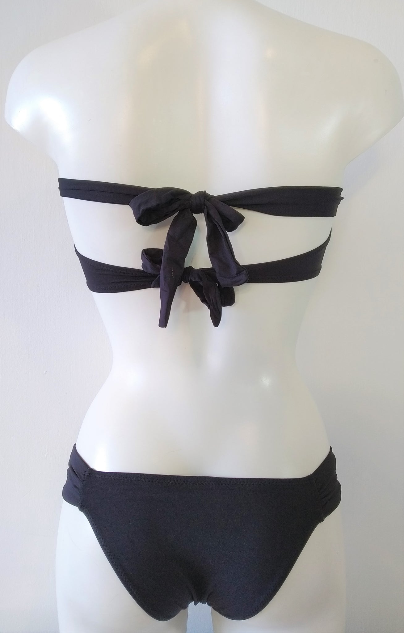 back view of black bikini swimsuit with a low cheeky bottom and strapless bra, two tied back straps