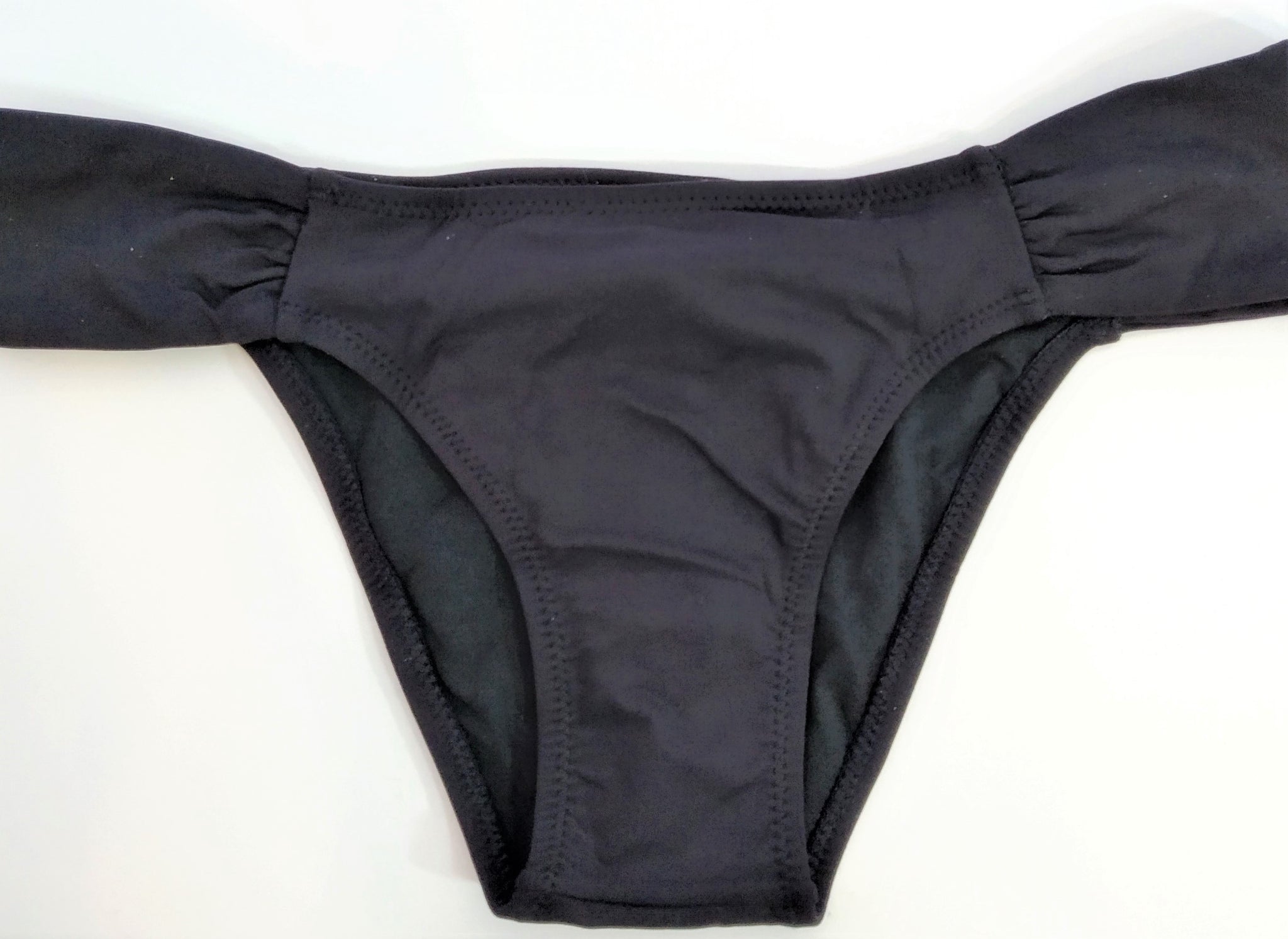 black swimsuit panties lay flat, part of a strapless black bikini set. at bikinn.com bikini collection