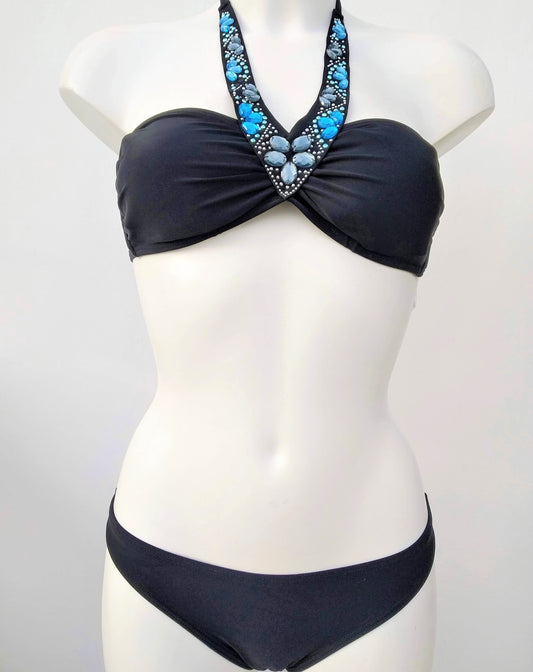 Presentation on a bust of a black bikini, bandeau and regular cut panties, with decoration of sparkling stones sewn along the neckline. bikinn.com