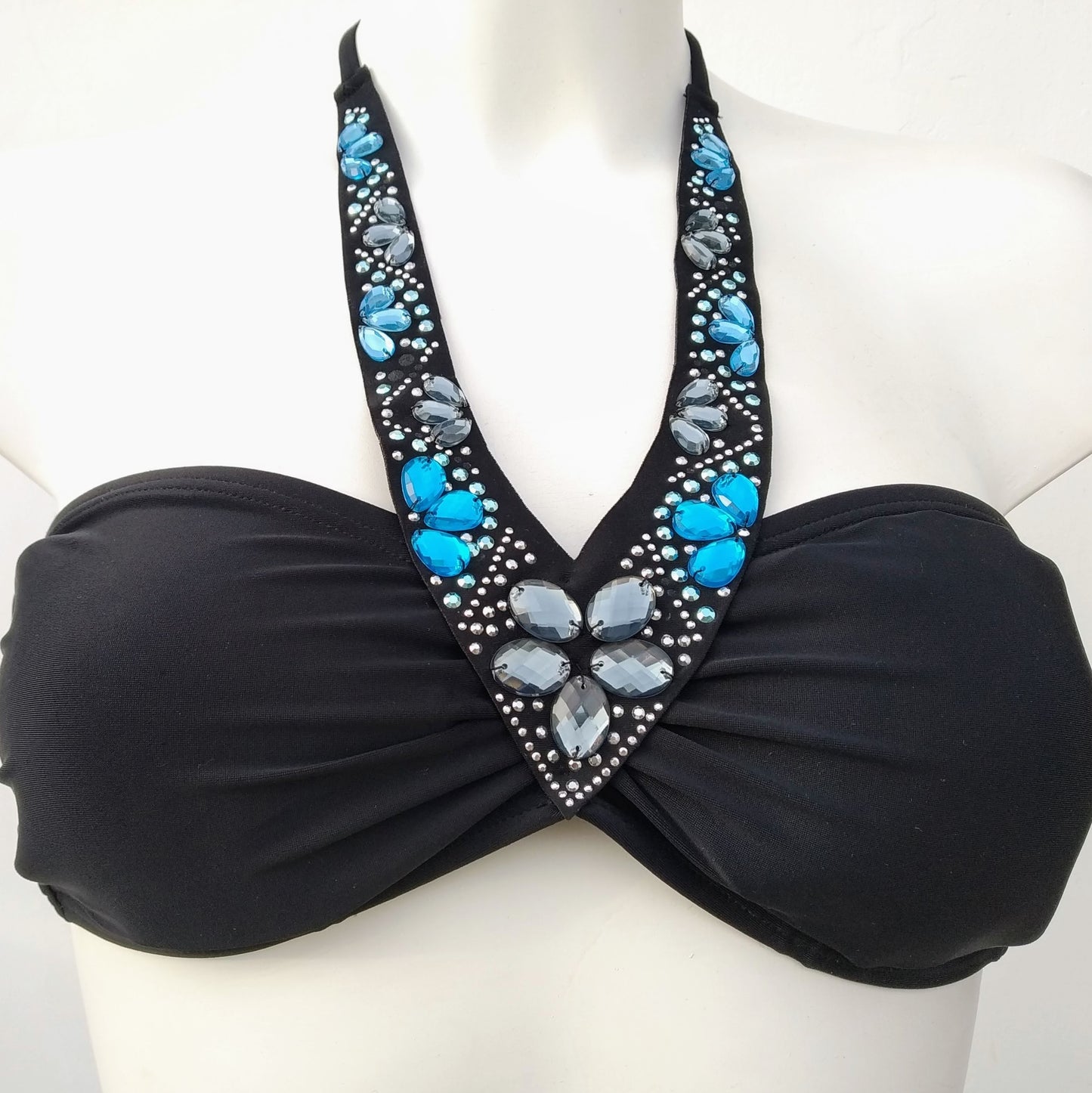 Presentation on a bust of a black bikini, bandeau and regular cut panties, with decoration of sparkling stones sewn along the neckline. bikinn.com