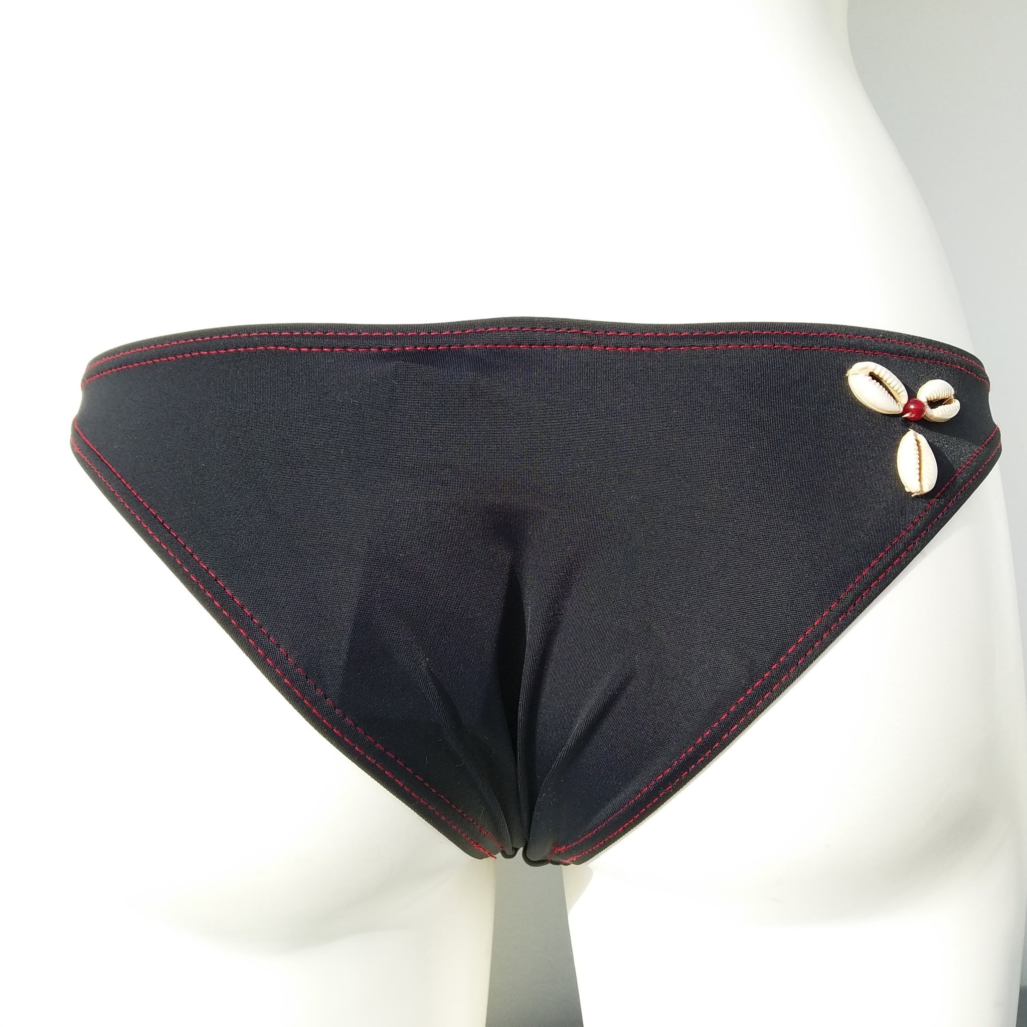 Back view of a black brazilian bikini bottom with 3 seashells sewn. bikinn.com