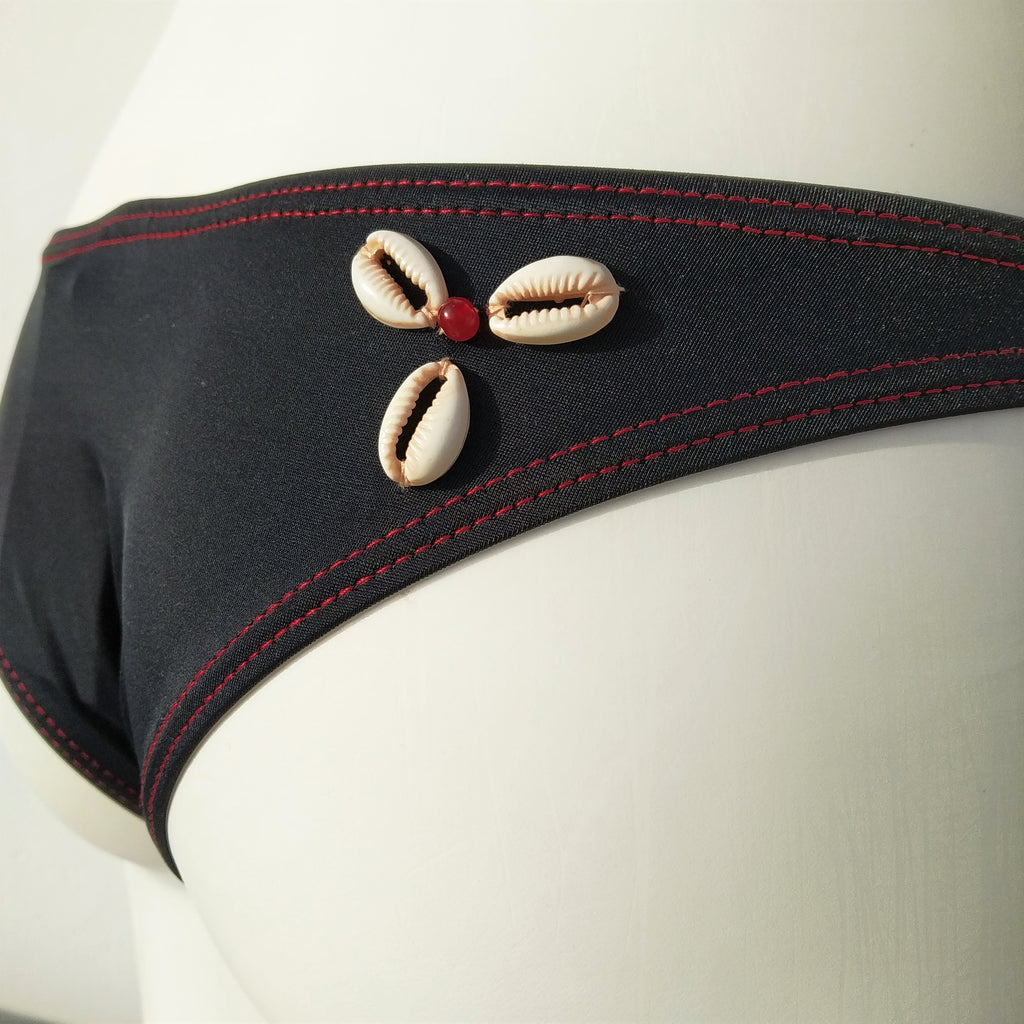Back view of a black brazilian bikini bottom with 3 seashells  sewn. bikinn.com