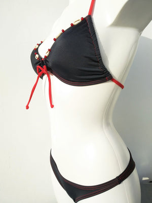 profile view of reversed black triangular bikini set with few seashells sewn for decoration along the neckline . bikinn.com