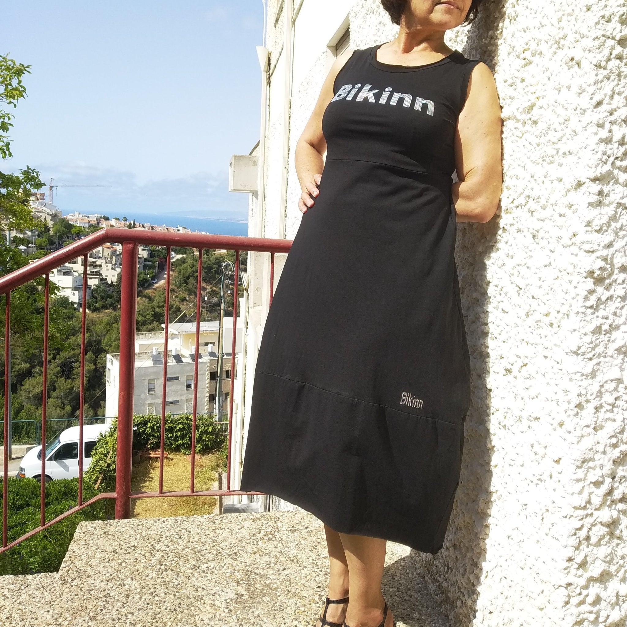 women standing outside wearing black sleeveless summer dress, Rhinestone hotfix print of Bikinn as front embellishment, Bling-bling fashion. bikinn.com