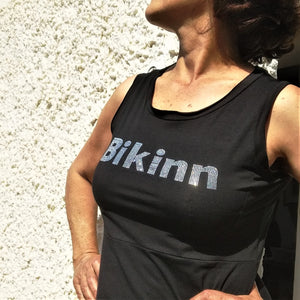 close-up of women standing outside wearing a black sleeveless summer dress, Rhinestone hotfix print of Bikinn as front embellishment, Bling-bling fashion. bikinn.com