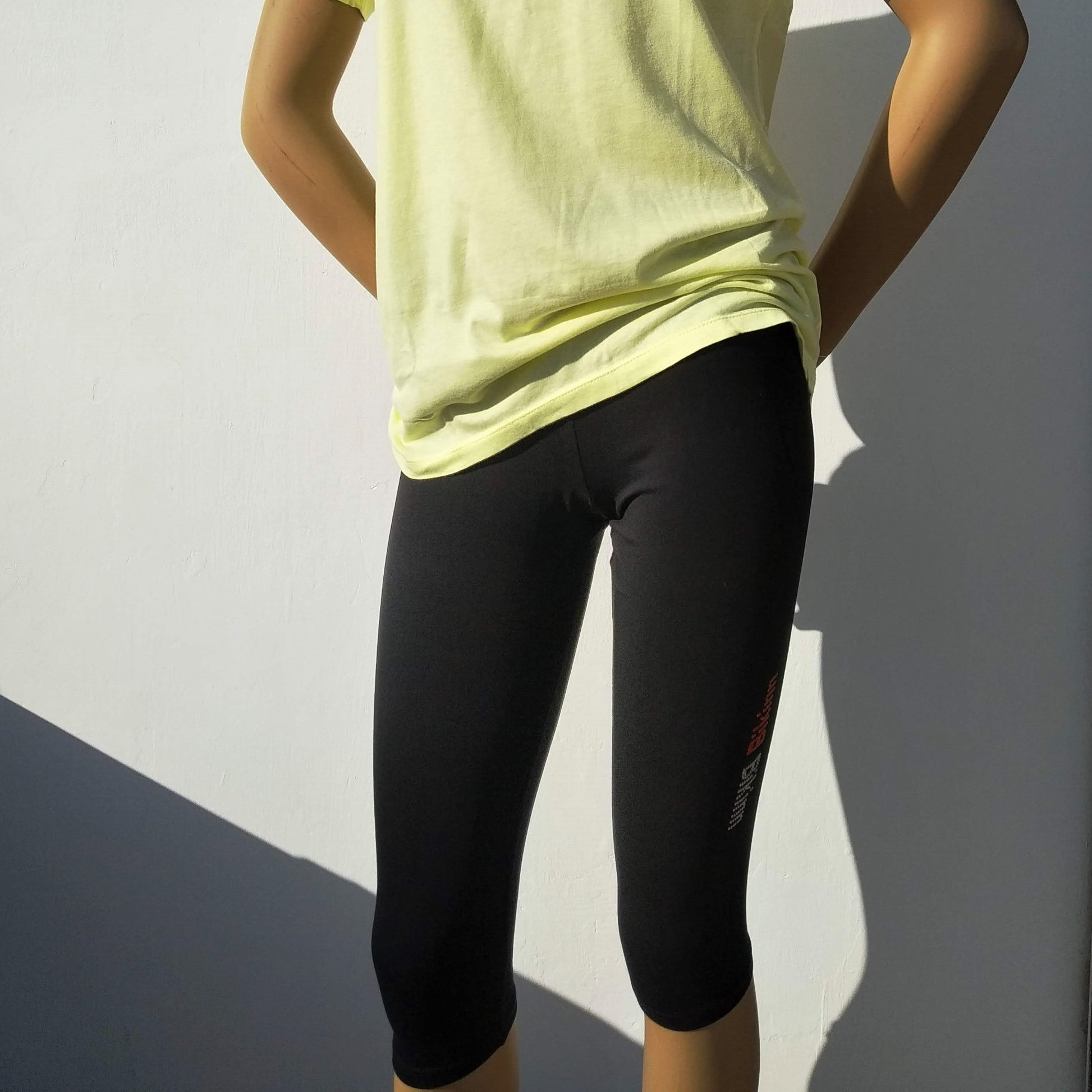 manequin wearing yellow short sleeves t-shirt and 3/4 lenght black leggings with rhinestones decoration on the side, bling-bling collection. bikinn.com