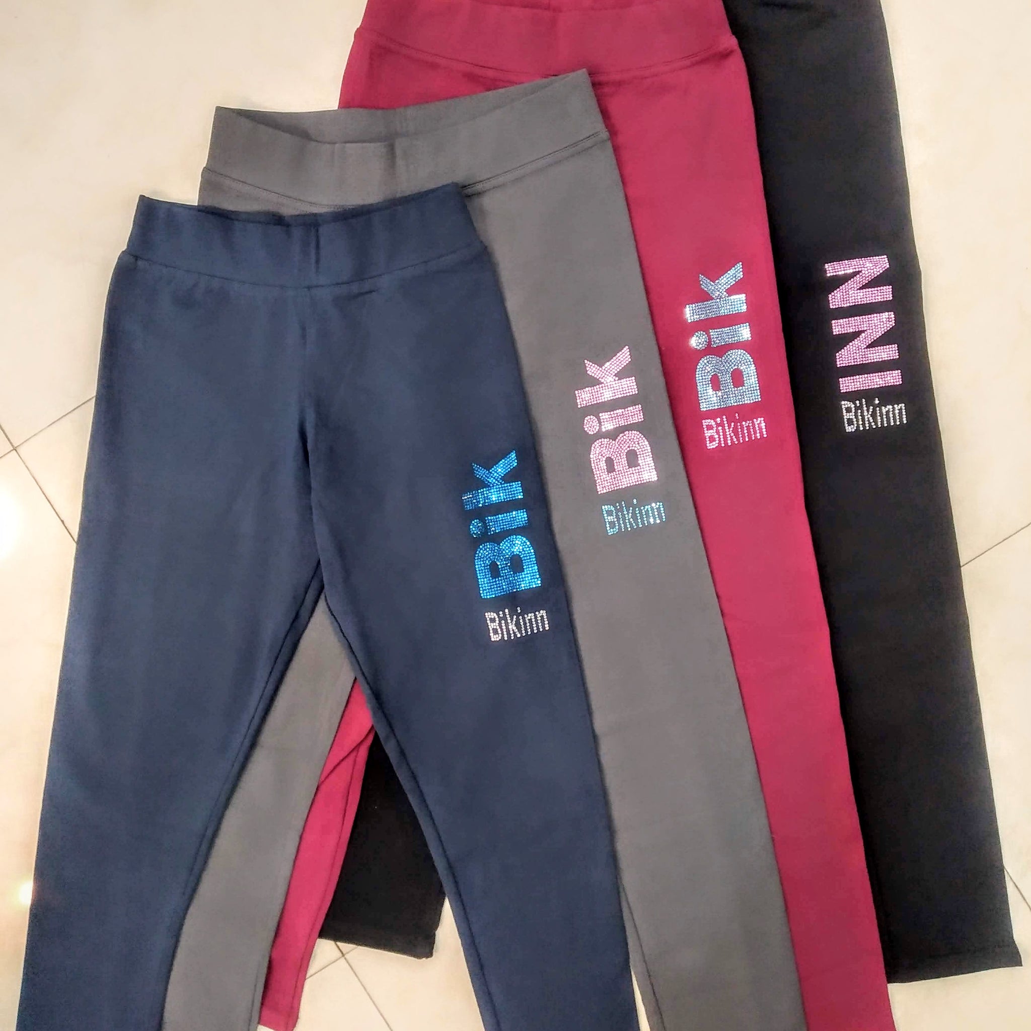 display of 4 different colors of long leggings with rhinestones crystals printed logo on left thigh, bling-bling fashion. bikinn.com