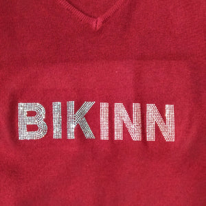 Detail of a fine cotton sweater, with a crystal logo printed on the front: "BIKINN". bikinn.com