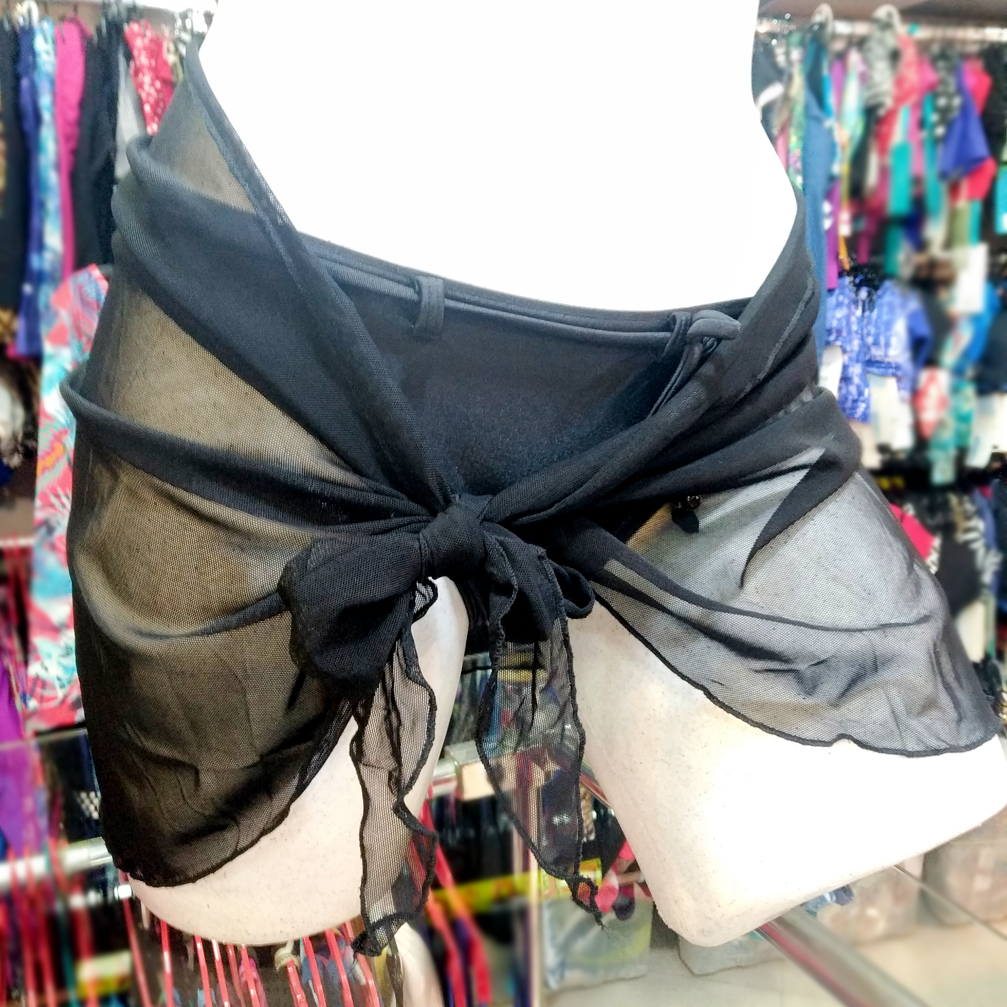 front view of a black mini stretchy pareo tied around a white mannequin wearing a black bikini bottom.