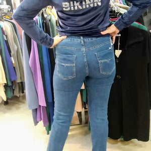 Back view of Woman in a skinny strech jeans with a sparkling diamond logo printed on the thigh. bikinn.com